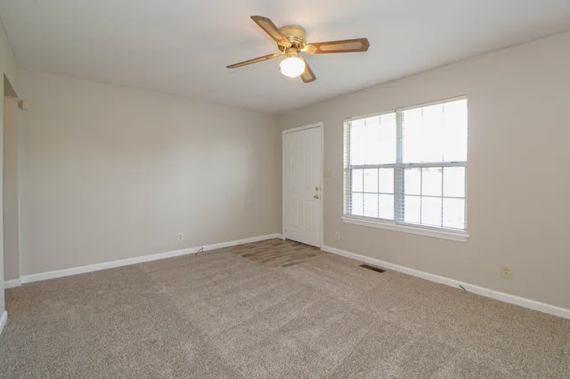 an empty room with a window and a fan