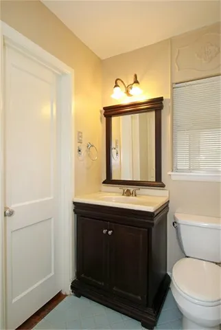 a bathroom with a granite countertop toilet sink and mirror