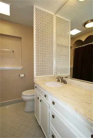 a bathroom with a granite countertop sink a toilet and a shower