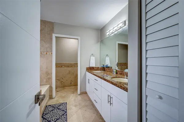 a bathroom with a granite countertop tub sink and mirror