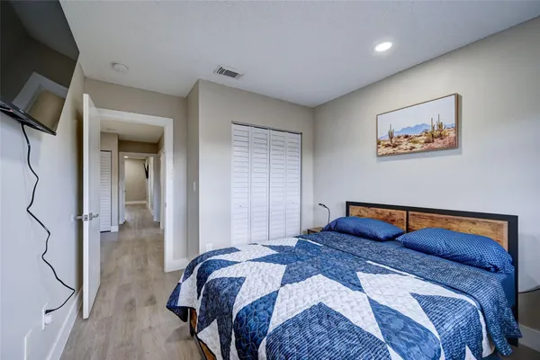 a bedroom with a bed and a lamp on dresser