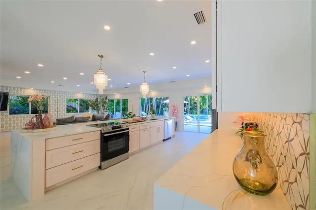 a kitchen with stainless steel appliances kitchen island granite countertop a stove a sink and a white cabinets