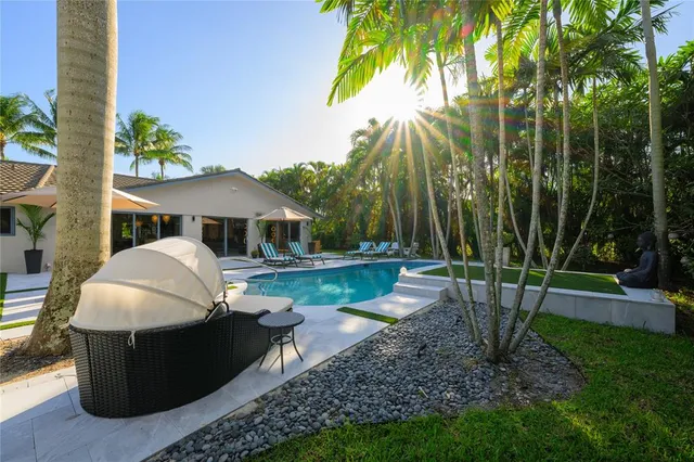 a couple of potted plants and palm trees in front of yellow house