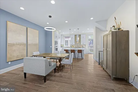 a living room with stainless steel appliances furniture refrigerator and a table