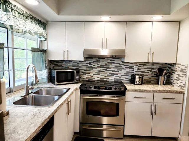 a kitchen with stainless steel appliances kitchen island a sink dishwasher a refrigerator and a counter space