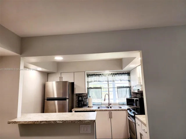a kitchen with granite countertop a refrigerator and a stove top oven
