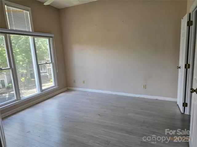 a view of an empty room with a window and wooden floor