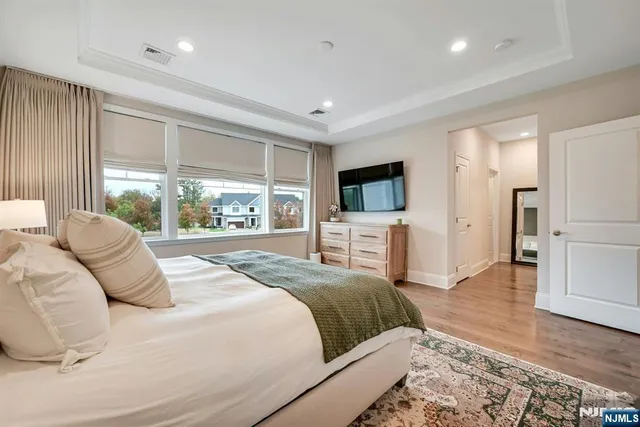 a bedroom with a large bed a large window and a flat tv screen