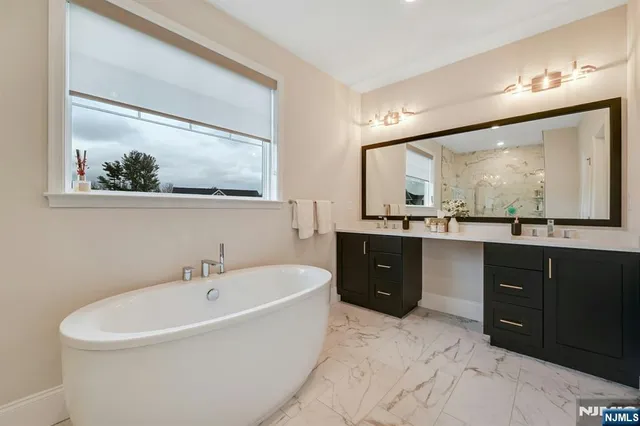 a spacious bathroom with a tub sink and mirror