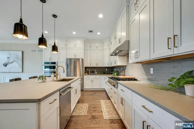 a kitchen with stainless steel appliances granite countertop a sink a stove and a refrigerator
