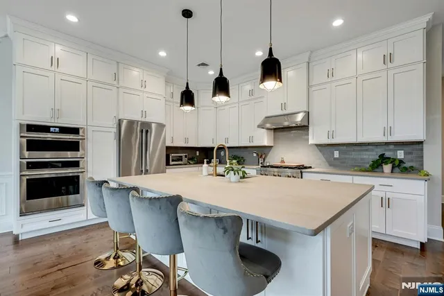 a kitchen with stainless steel appliances granite countertop a stove a refrigerator a oven a sink a dining table and chairs with wooden floor