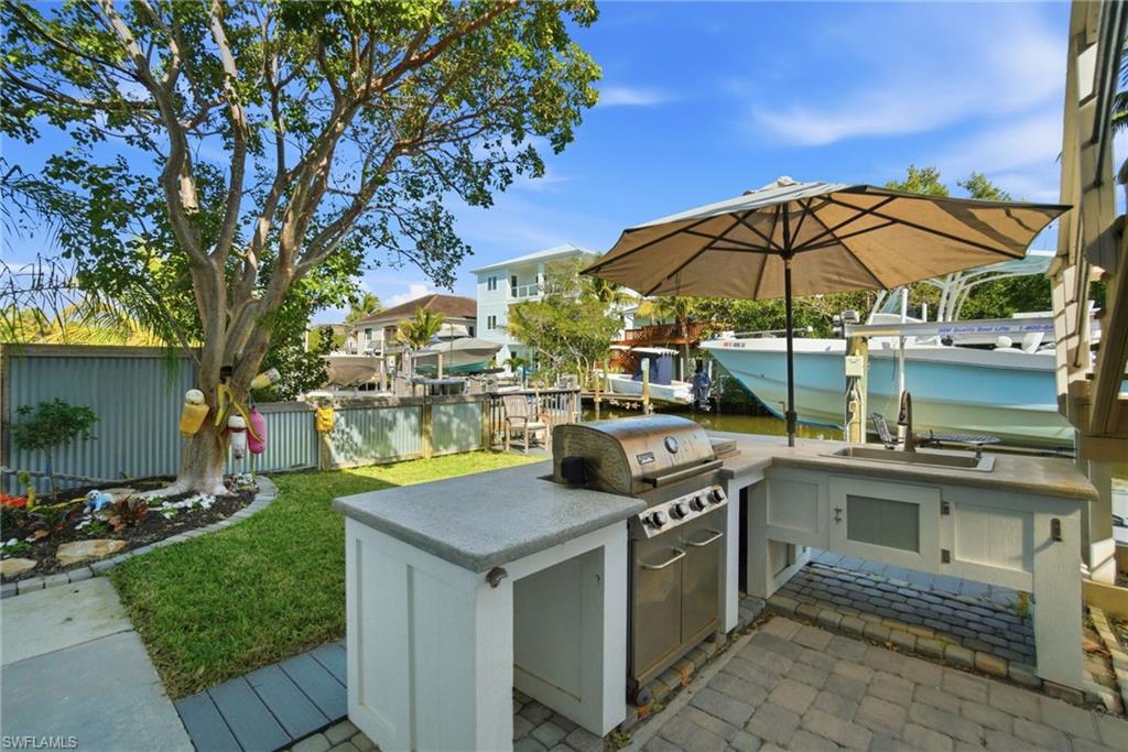 1286 Venetian Way Naples, FL 34110 - Photo 31 of 46 a view of a kitchen with a sink and table under an umbrella