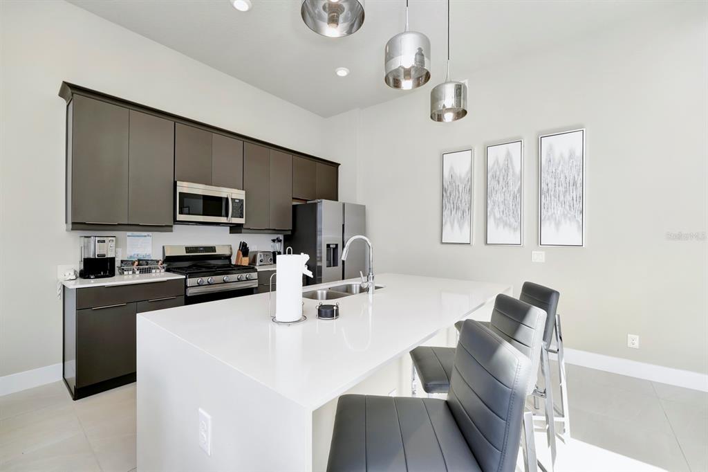 7740 Sandy Ridge Drive, Unit 220 Reunion, FL 34747 - Photo 12 of 55 a kitchen with stainless steel appliances granite countertop a sink dishwasher a stove top oven a refrigerator with island and chairs