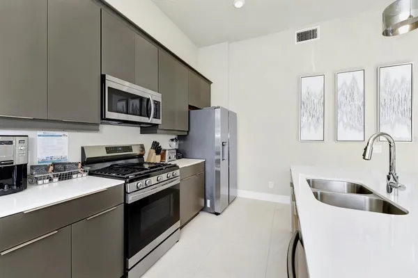 a kitchen with stainless steel appliances a stove a sink a refrigerator white cabinets and a refrigerator