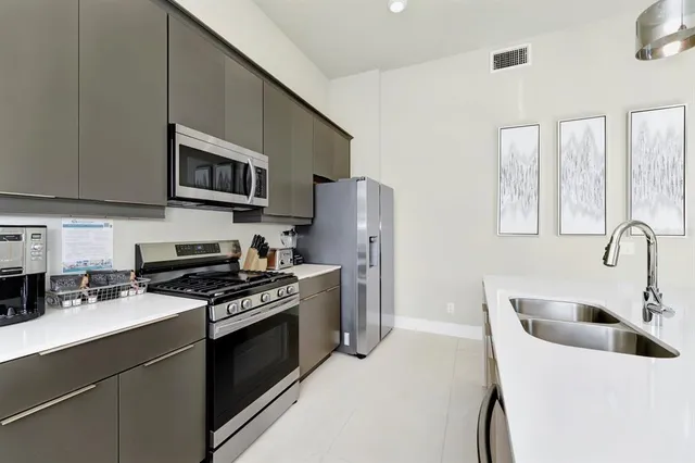 a kitchen with stainless steel appliances a stove a sink a refrigerator white cabinets and a refrigerator