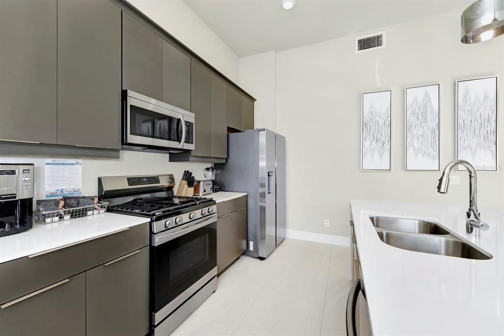 7740 Sandy Ridge Drive, Unit 220 Reunion, FL 34747 - Photo 14 of 55 a kitchen with stainless steel appliances a stove a sink a refrigerator white cabinets and a refrigerator