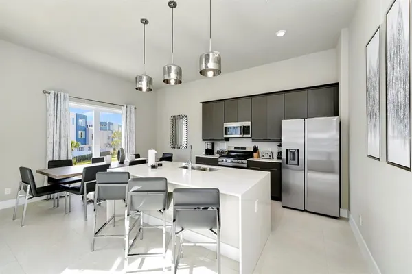 a room with stainless steel appliances kitchen island granite countertop a refrigerator a stove top oven a sink dishwasher and a dining table with wooden floor