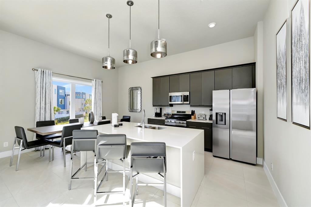 7740 Sandy Ridge Drive, Unit 220 Reunion, FL 34747 - Photo 17 of 55 a room with stainless steel appliances kitchen island granite countertop a refrigerator a stove top oven a sink dishwasher and a dining table with wooden floor