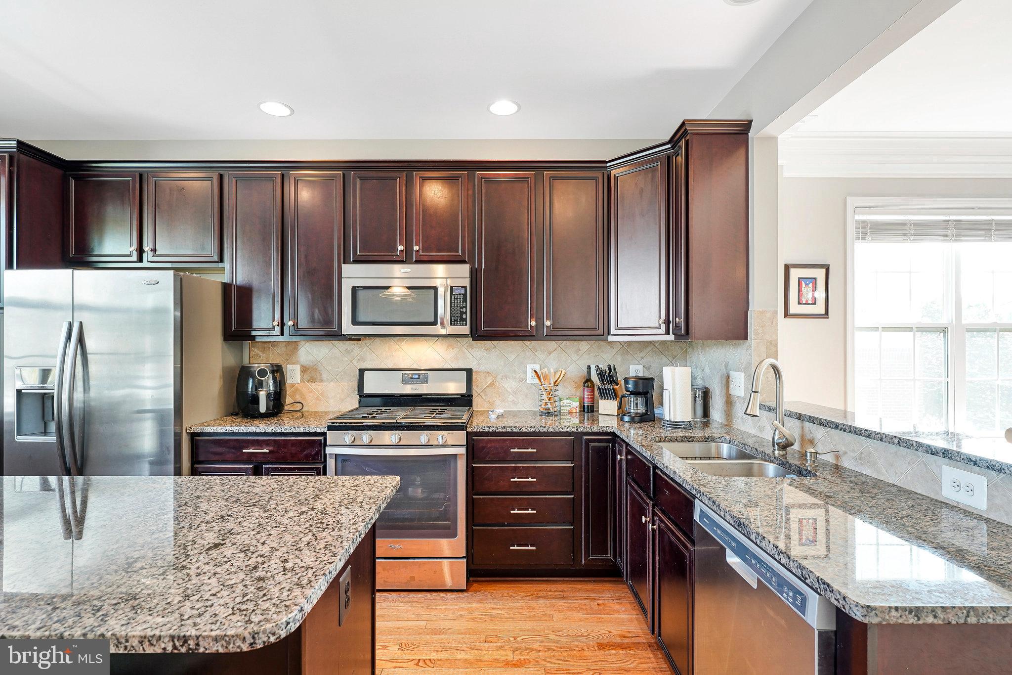 23073 Weybridge Square Broadlands, VA 20148 - Photo 8 of 24 a kitchen with stainless steel appliances granite countertop a sink stove microwave and refrigerator