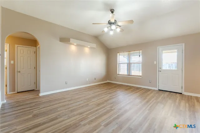 a view of an empty room with wooden floor and a window