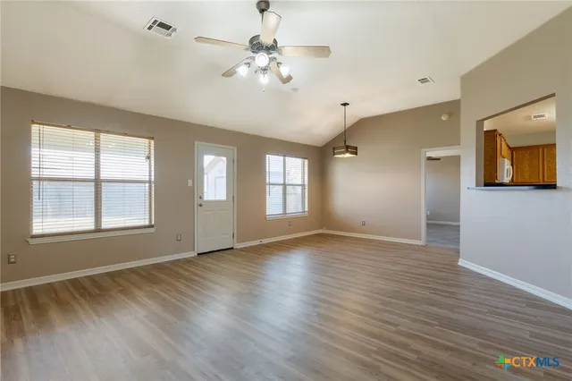 a view of an empty room with a window and wooden floor