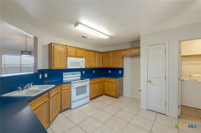 a large kitchen with a stove a sink dishwasher and a refrigerator