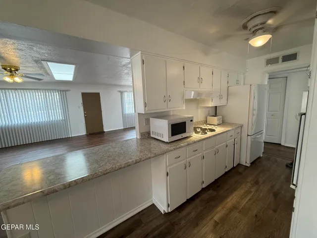 a large kitchen with a lot of counter space and wooden floor