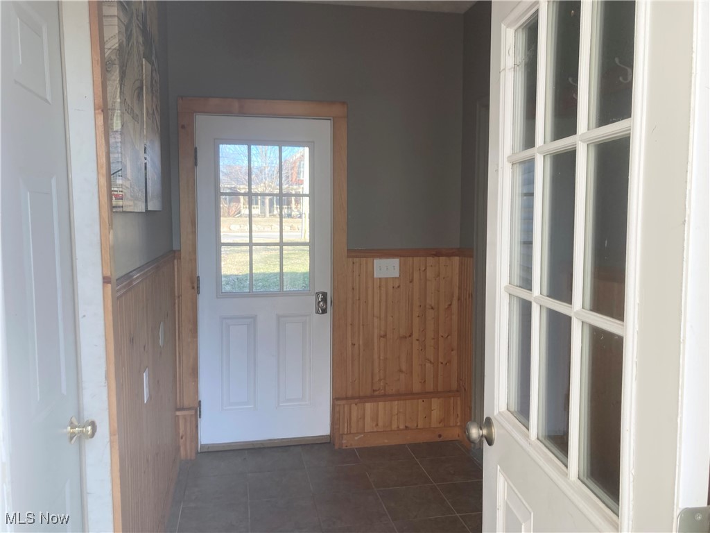 3510 Long Road Avon, OH 44011 - Photo 9 of 26 Doorway with wainscoting, wood walls, and dark tile patterned flooring