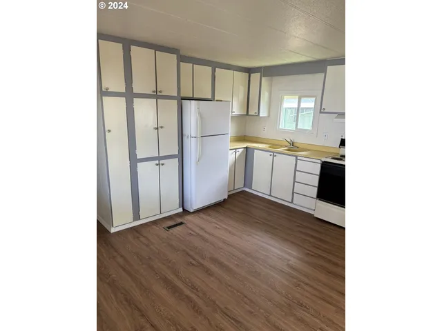 a kitchen with a refrigerator and white cabinets