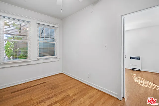 a view of empty room with wooden floor and fan