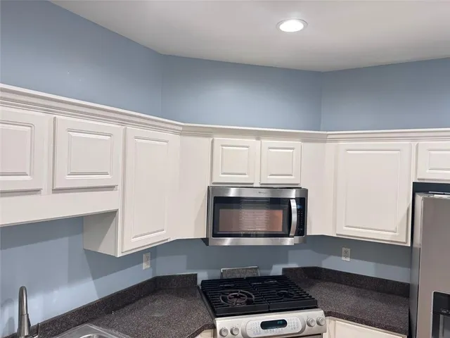 a kitchen with stainless steel appliances a stove a microwave and white cabinets