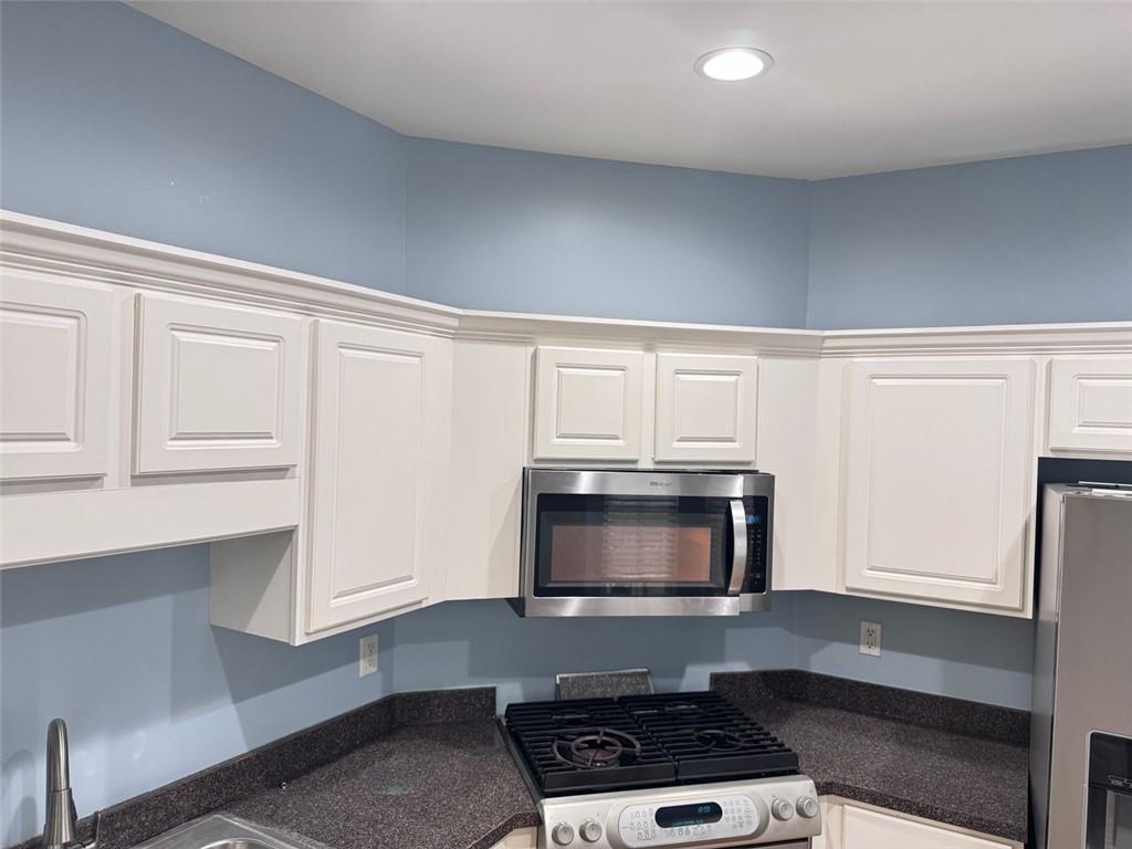 5495 Hampton Court Atlanta, GA 30349 - Photo 18 of 20 a kitchen with stainless steel appliances a stove a microwave and white cabinets