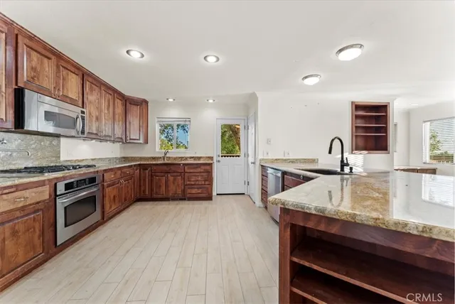 a kitchen with stainless steel appliances granite countertop a sink window and cabinets