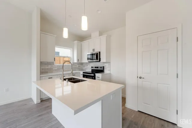 a kitchen with a sink a stove a microwave and wooden floor