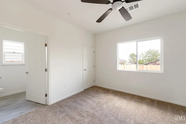 a view of a big room with windows and chandelier fan