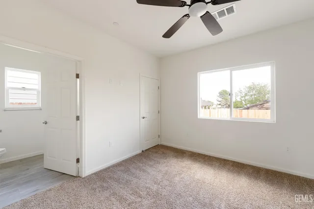 a view of a big room with windows and chandelier fan