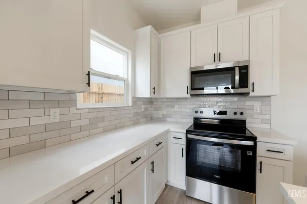 a kitchen with stainless steel appliances a stove a microwave a sink and cabinets