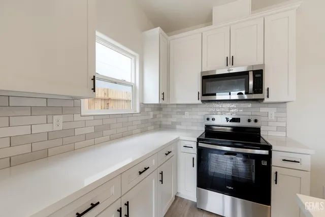 a kitchen with stainless steel appliances a stove a microwave a sink and cabinets