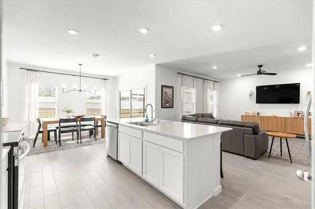 a dining room with wooden floor a chandelier a wooden table and chairs