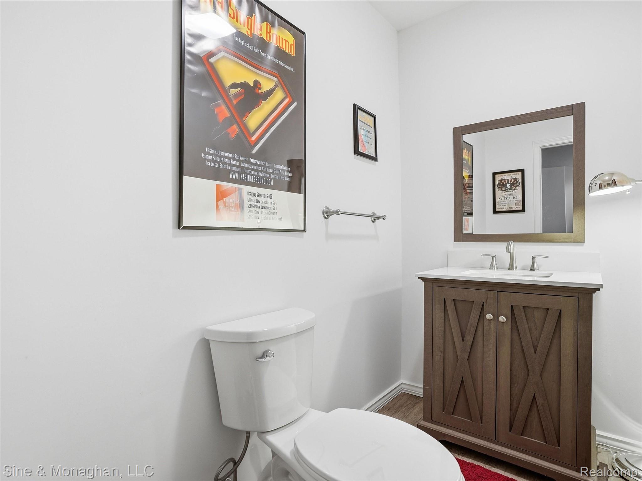 24827 Ivy Road Novi, MI 48375 - Photo 31 of 38 Powder room featuring a wood-finish vanity with X-panel doors, an undermount sink, a light-toned countertop, and brushed nickel fixtures