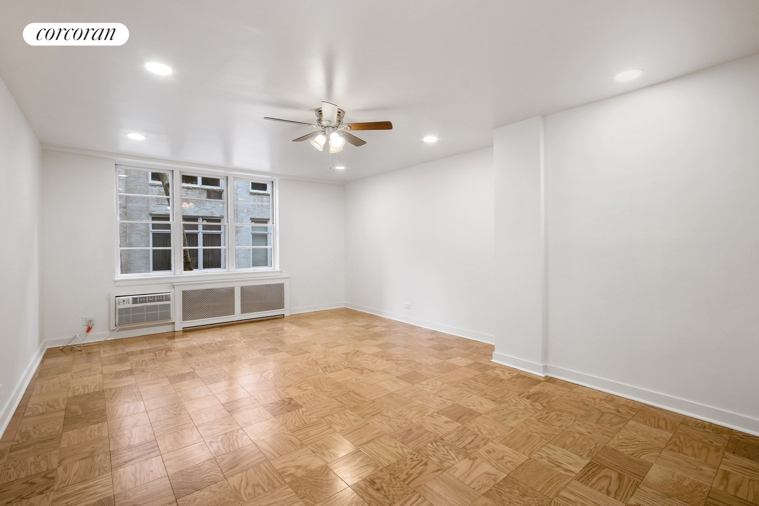 an empty room with windows and ceiling fan