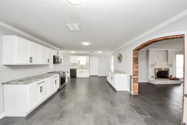 a large kitchen with a lot of counter space and wooden floor