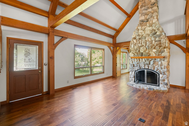 435 Canyon Road Millville, UT 84326 - Photo 8 of 113 Spacious living area featuring a floor-to-ceiling stone fireplace, vaulted ceilings with exposed wood beams, and rich wood-finish flooring