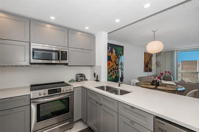 a kitchen with stainless steel appliances a stove a sink a microwave oven a refrigerator white cabinets and a microwave