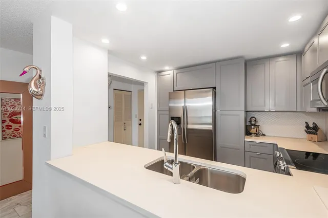 a kitchen with stainless steel appliances kitchen island a sink a refrigerator and cabinets
