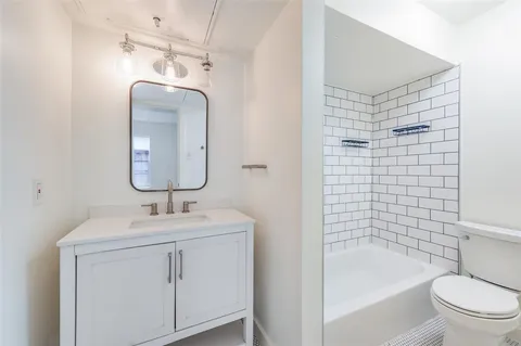a bathroom with a toilet a sink a mirror a bathtub and shower