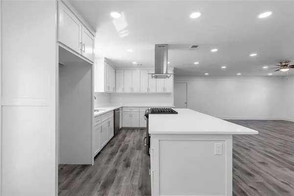 a kitchen with a sink a stove cabinets and wooden floor