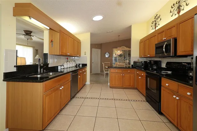 a large kitchen with stainless steel appliances granite countertop a stove a sink and a microwave