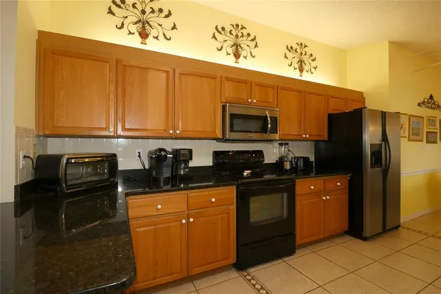 a kitchen with granite countertop a refrigerator stove and microwave