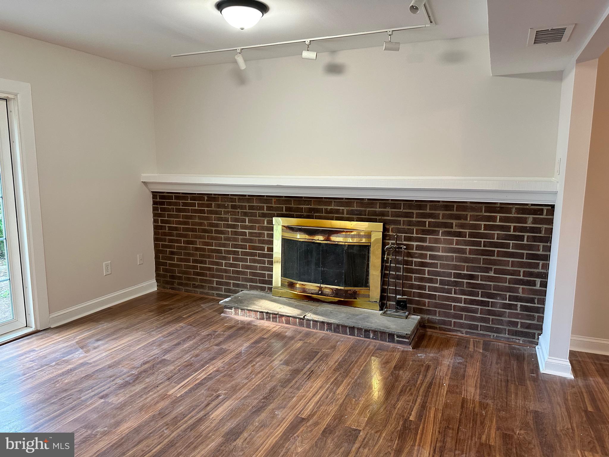 17209 Chiswell Road Poolesville, MD 20837 - Photo 8 of 21 a view of an empty room with wooden floor a fireplace and a window